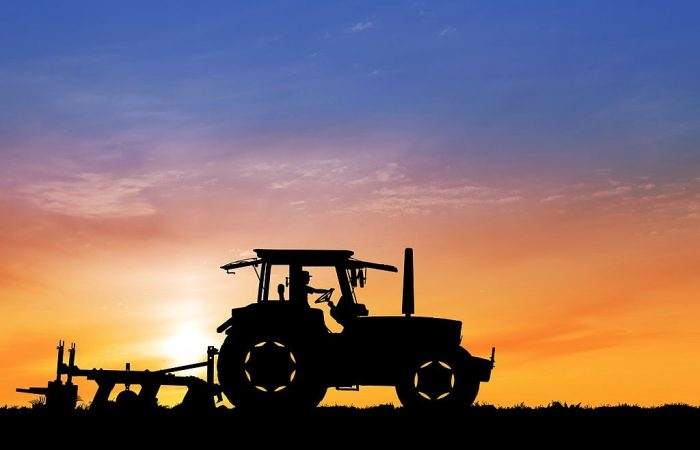 Tractor in field carrying out agric mechanization while the sun sets