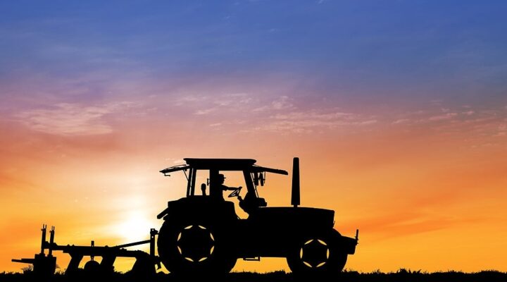 Tractor in field carrying out agric mechanization while the sun sets